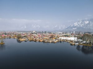 Stunning aerial view of Srinagar's Dal Lake with a backdrop of snowy mountains.